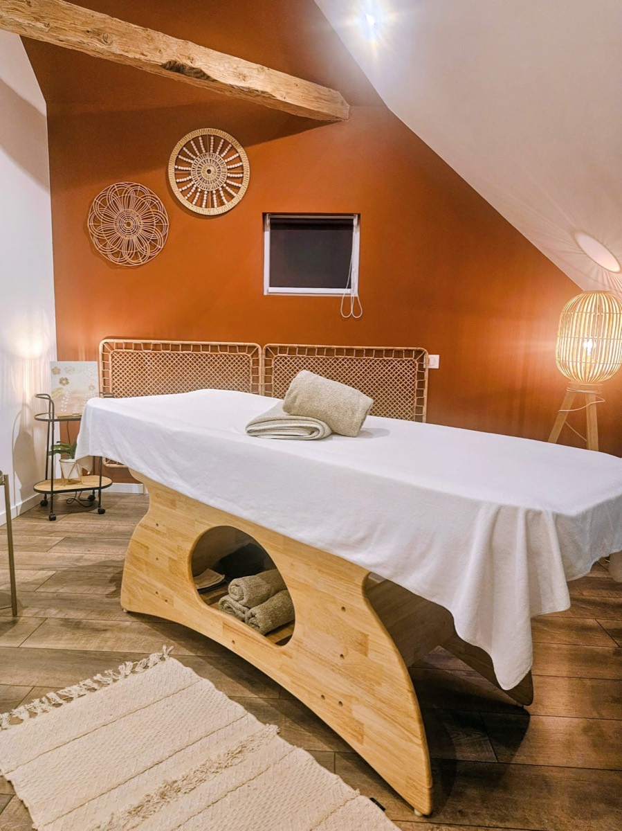 Table de massage de l'Institut de Sidonie devant un mur terracotta, décor en rotin et lumière tamisée